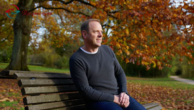 Мужчина сидит на лавочке в парке